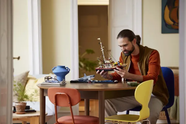 An adult LEGO builder assembling a detailed LEGO Ideas set - official LEGO lifestyle photo