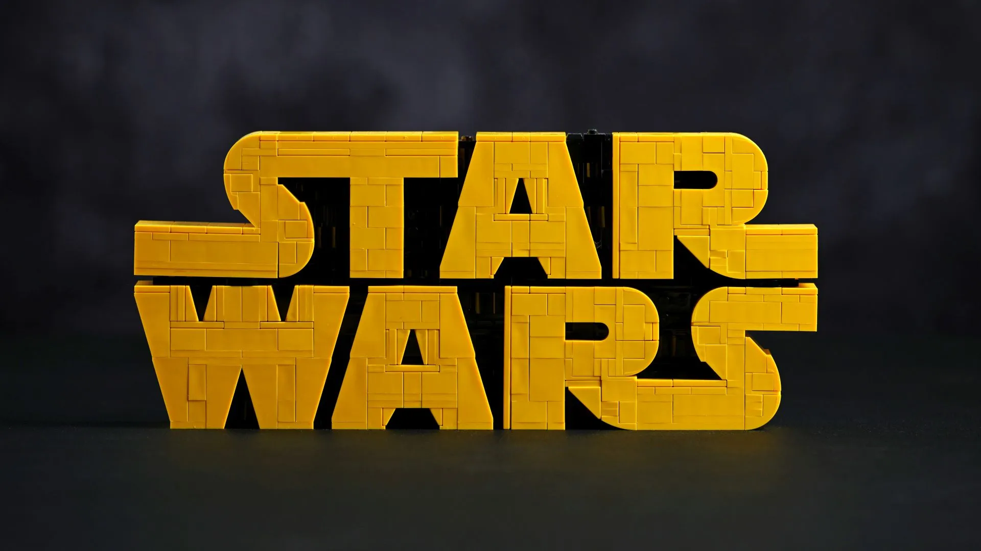 LEGO Star Wars Brick-Built Star Wars Logo (75407) The finished LEGO Star Wars Brick-Built Star Wars Logo (75407) in yellow bricks against a dark background