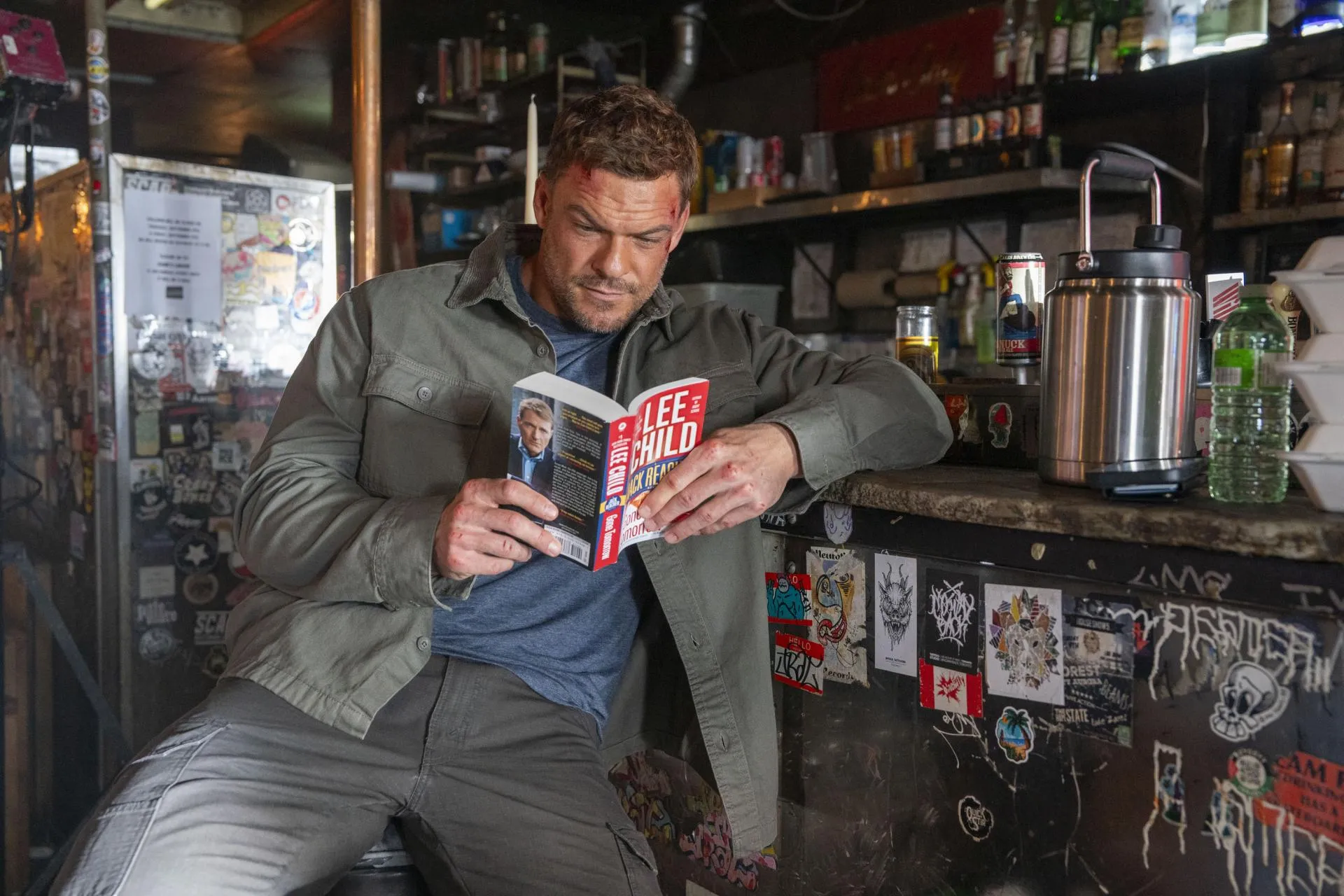 Reacher – Season 4 on Prime Video: Gone Tomorrow, Done Right A bruised Alan Ritchson as Jack Reacher reading a Lee Child paperback at a dive bar counter in Reacher season 4